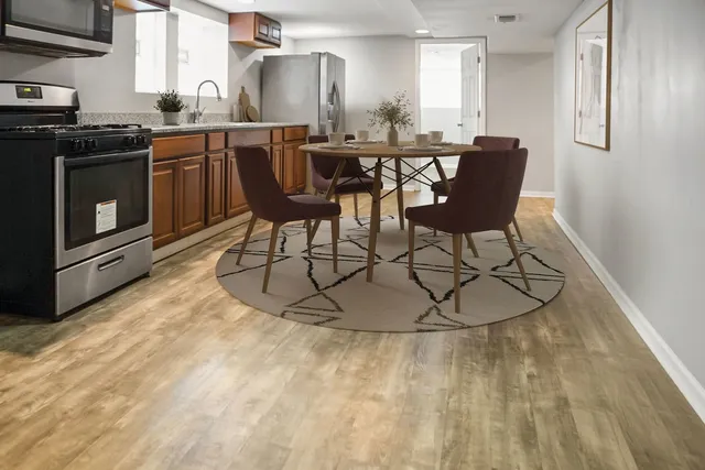 a kitchen with stainless steel appliances a dining table chairs and a refrigerator