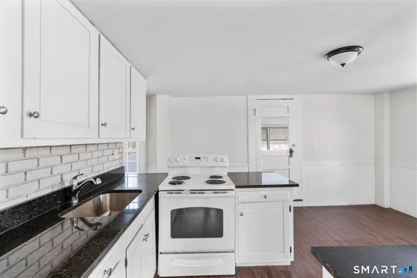 a kitchen with granite countertop a sink a stove and cabinets
