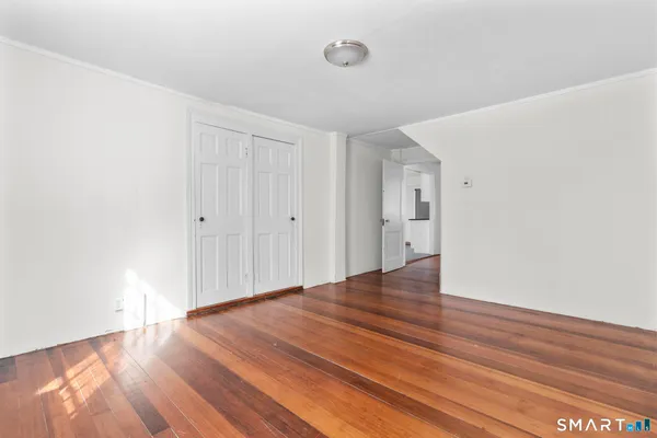 a view of empty room with wooden floor and window