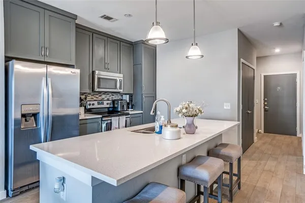 a kitchen with stainless steel appliances a dining table chairs refrigerator and cabinets