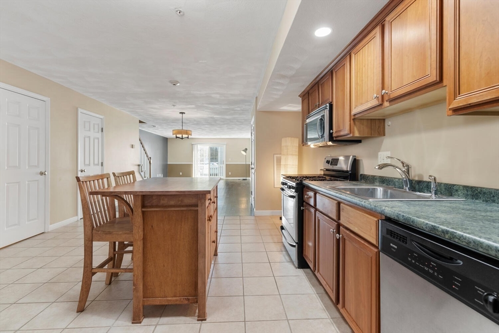 18 Dale Street, Unit 9D Andover, MA 01810 - Photo 8 of 33 a kitchen with stainless steel appliances granite countertop a table chairs sink and cabinets