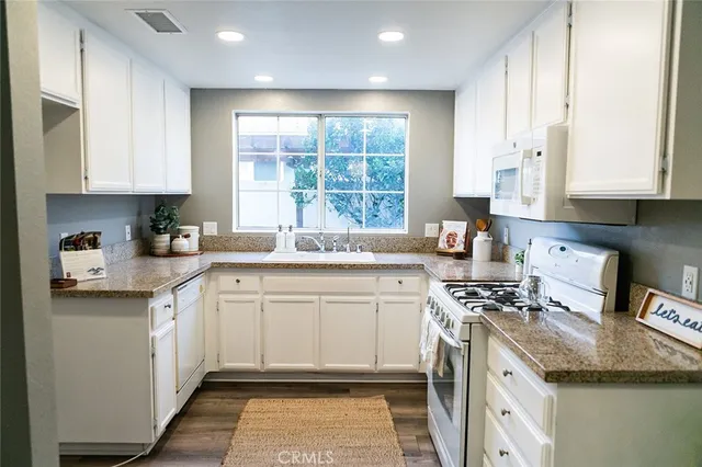 a kitchen with granite countertop a sink stove and cabinets