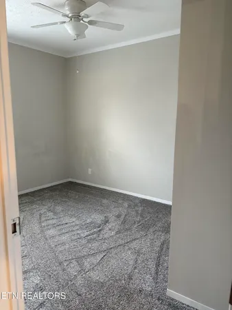 an empty room with a ceiling fan and carpet