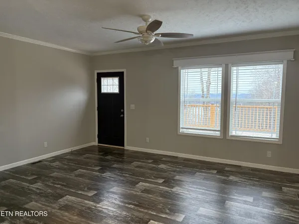 a view of an empty room with window and wooden floor