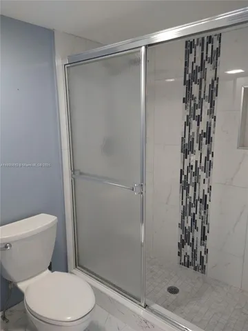 a white toilet sitting next to a shower