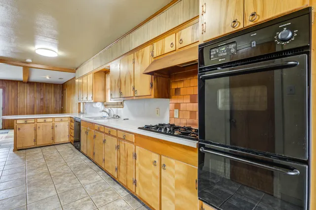 a large white kitchen with a sink and dishwasher a stove top oven with wooden floor