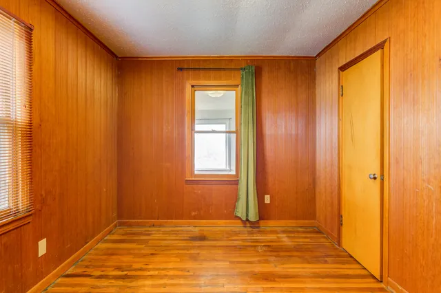 an empty room with wooden floor fan and windows