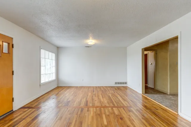 a view of empty room with wooden floor and fan