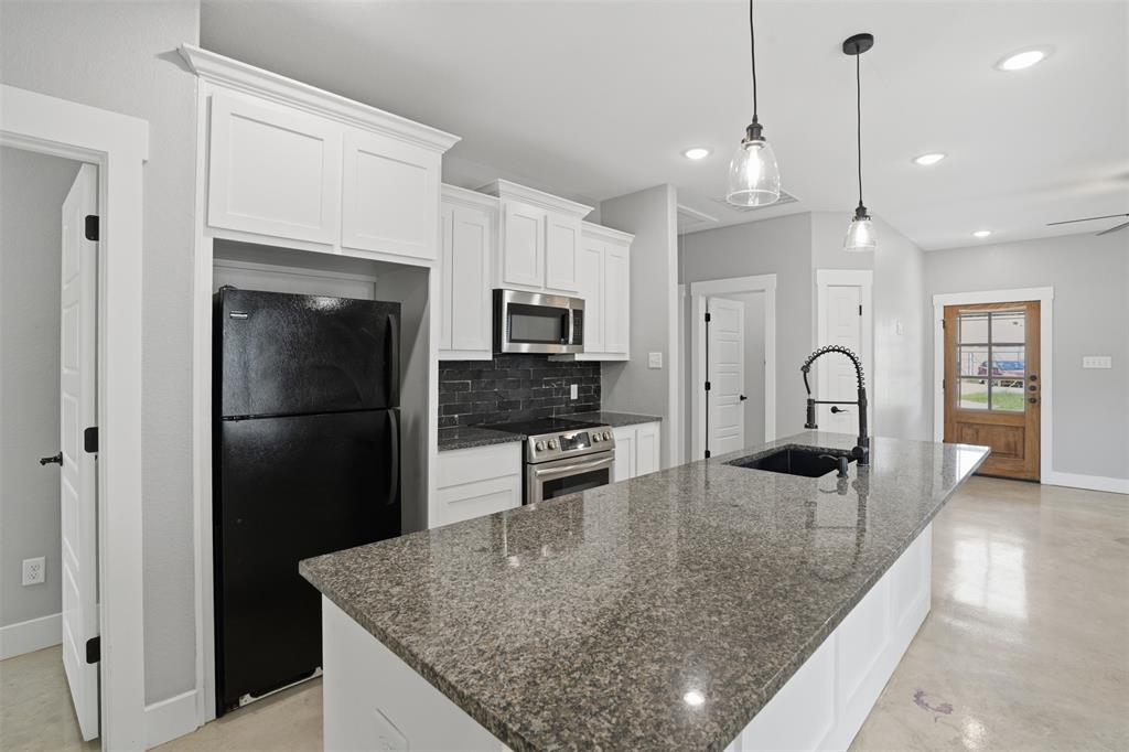 738 East Sears Street Denison, TX 75021 - Photo 11 of 32 a kitchen with stainless steel appliances granite countertop a refrigerator a stove and a sink with wooden floor