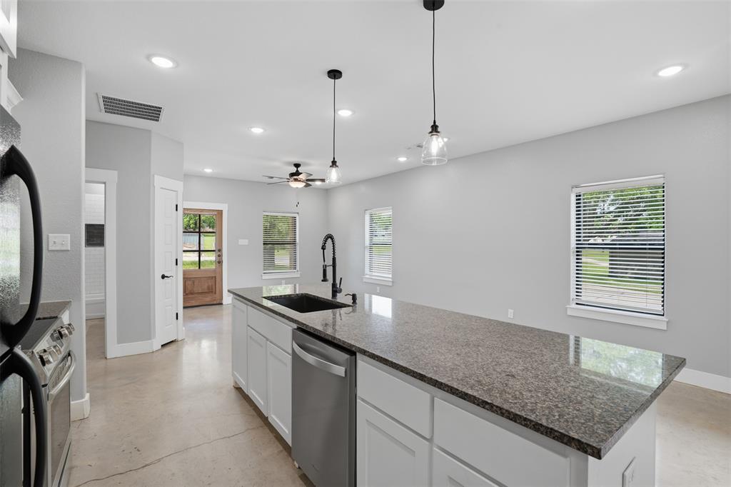 738 East Sears Street Denison, TX 75021 - Photo 13 of 32 a kitchen with granite countertop stainless steel appliances a sink a counter top space cabinets and a window