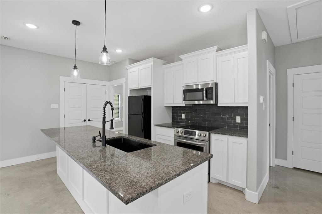 738 East Sears Street Denison, TX 75021 - Photo 15 of 32 a kitchen with stainless steel appliances granite countertop a sink refrigerator and microwave