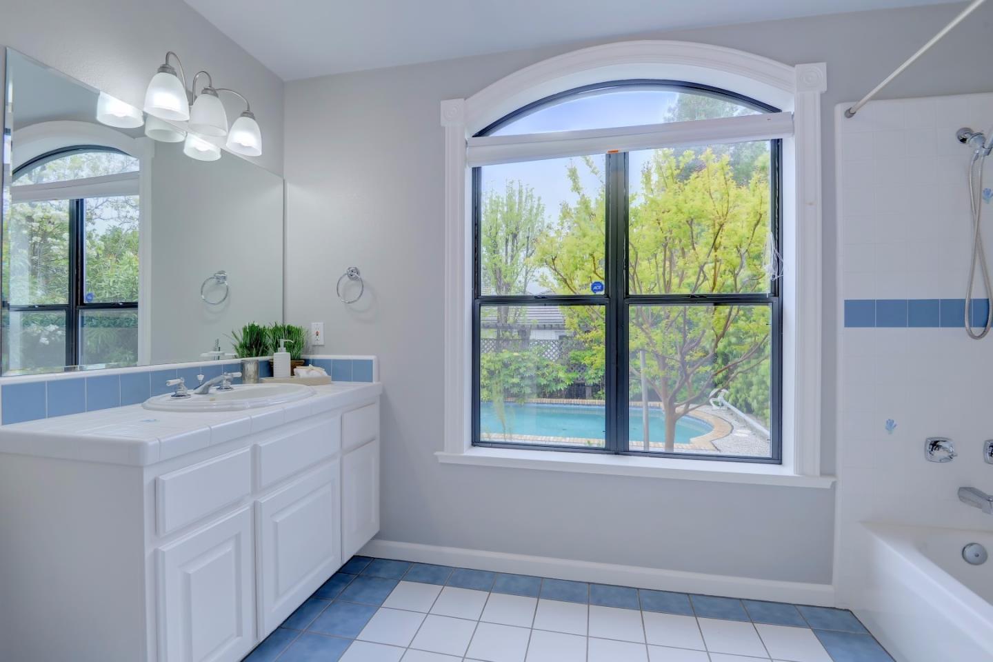 6802 Graystone Lane San Jose, CA 95120 - Photo 20 of 38 a bathroom with a sink a large mirror and a bathtub with shower