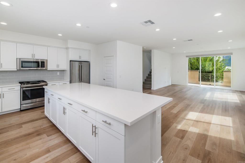 6140 Colt Place, Unit 104 Carlsbad, CA 92009 - Photo 12 of 37 a kitchen with kitchen island white cabinets and stainless steel appliances