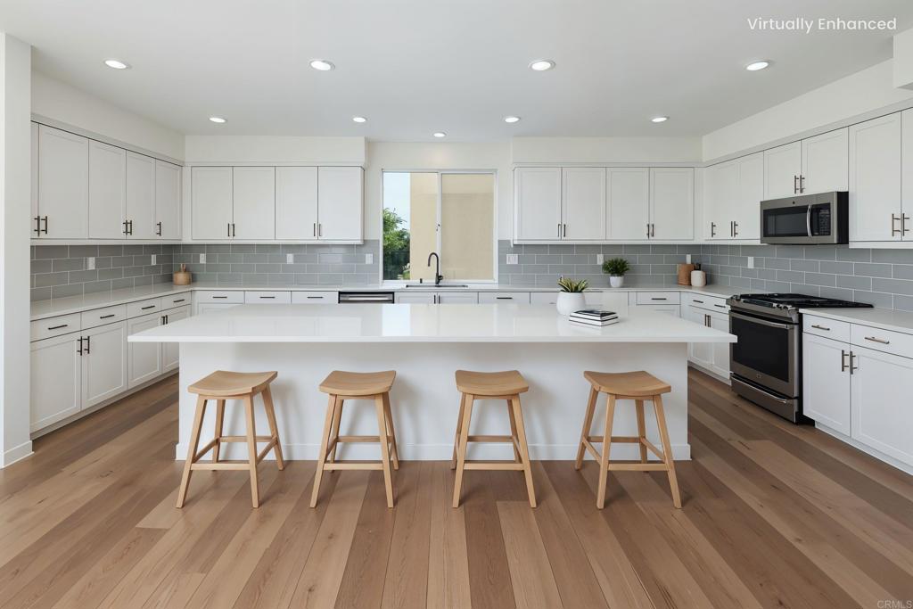 6140 Colt Place, Unit 104 Carlsbad, CA 92009 - Photo 2 of 37 a kitchen with stainless steel appliances granite countertop a table chairs sink microwave and cabinets