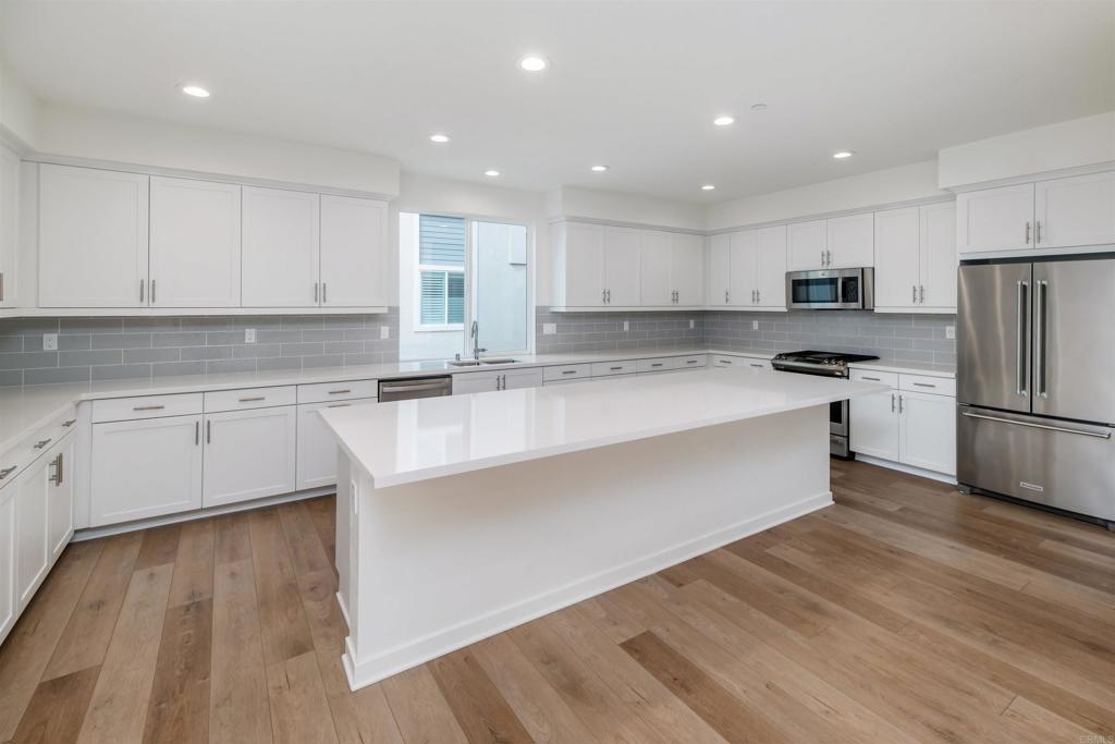 6140 Colt Place, Unit 104 Carlsbad, CA 92009 - Photo 9 of 37 a kitchen with a refrigerator a stove top oven and white cabinets