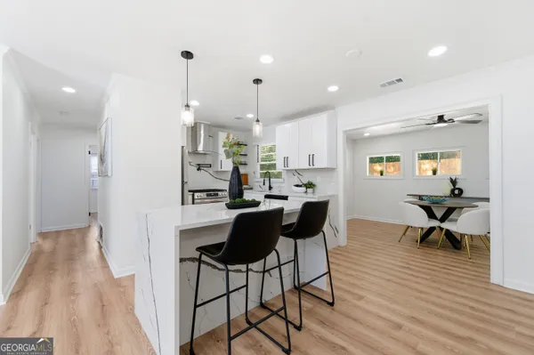 a kitchen with stainless steel appliances kitchen island granite countertop a refrigerator a stove a sink dishwasher and a dining table with wooden floor