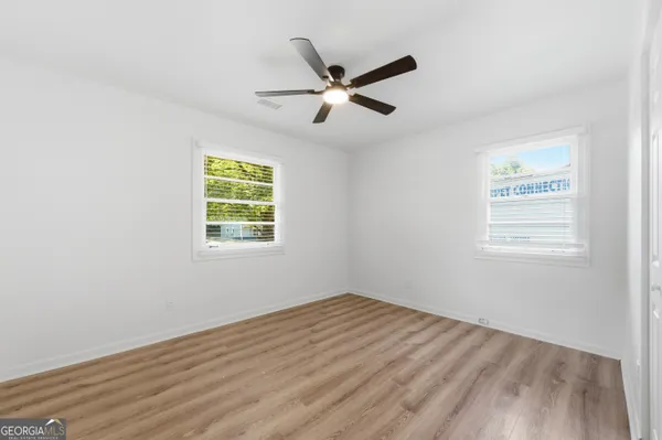 a view of empty room with wooden floor and ceiling fan
