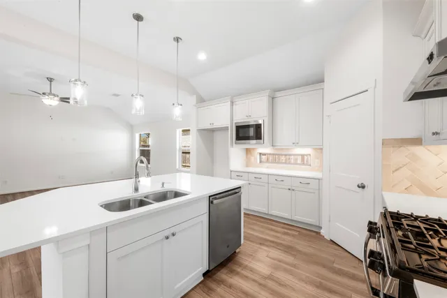 a kitchen with a sink dishwasher a stove a dining table and chairs with wooden floor