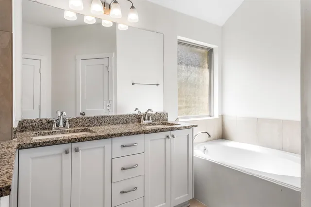 a bathroom with a granite countertop sink mirror and a bathtub