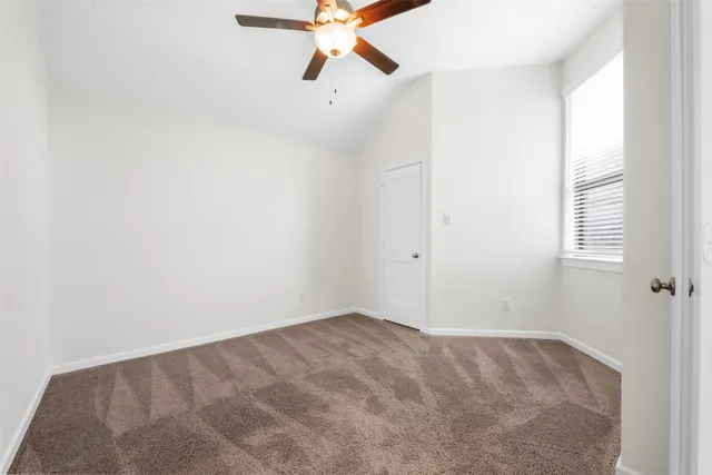 an empty room with a window and a ceiling fan
