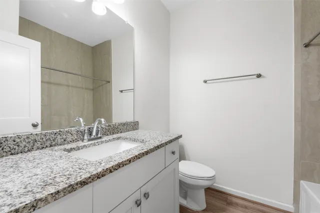a bathroom with a granite countertop sink a toilet and a mirror