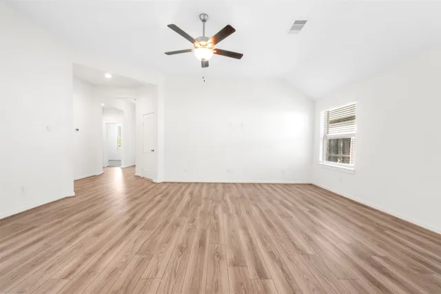 an empty room with wooden floor and a ceiling fan