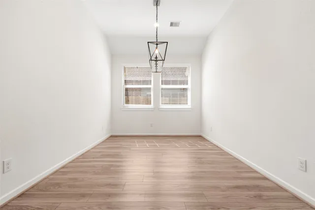 an empty room with wooden floor cabinet and windows