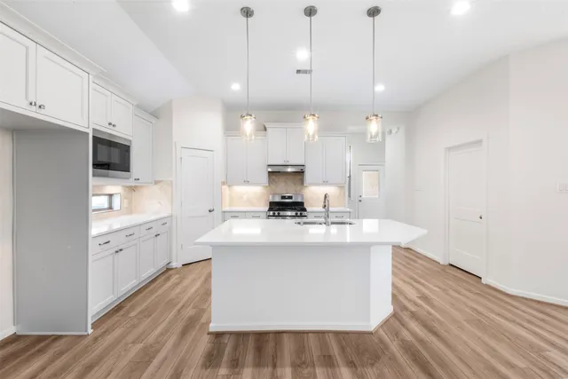 a large kitchen with kitchen island a stove a sink a center island and wooden floor