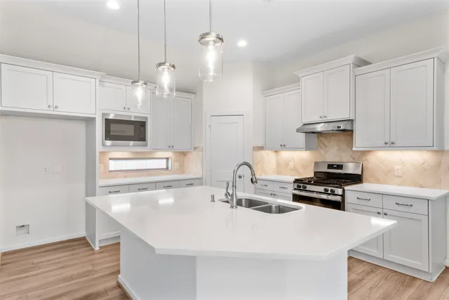 a kitchen with stainless steel appliances a stove a sink a refrigerator and cabinets