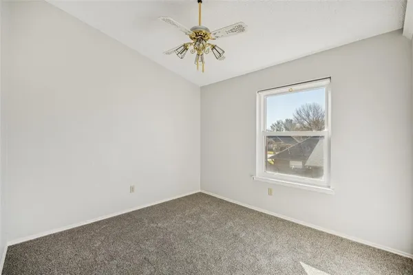 an empty room with windows and a chandelier fan