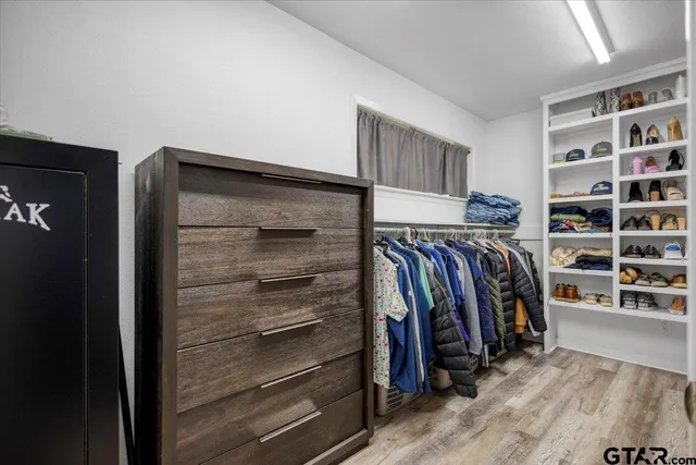 a view of walk in closet with clothes and shoes