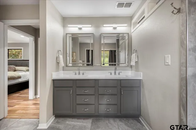 a en suite bathroom with a double vanity sink and a mirror