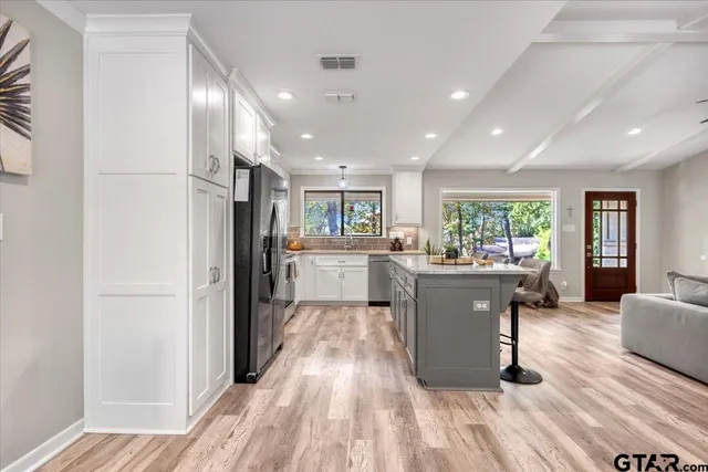 a living room with stainless steel appliances kitchen island granite countertop furniture and a refrigerator