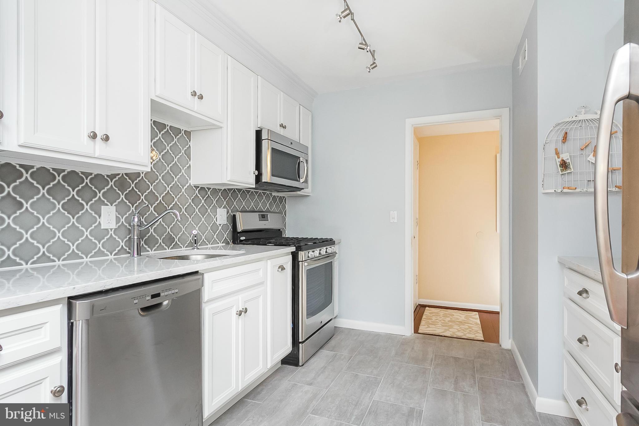 119 Cross Keys Road, Unit R119E Baltimore, MD 21210 - Photo 5 of 22 a kitchen with stainless steel appliances granite countertop a refrigerator a stove a sink and white cabinets with wooden floor