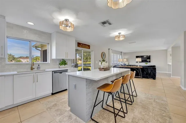 a kitchen with stainless steel appliances kitchen island granite countertop a sink a stove a dining table and chairs