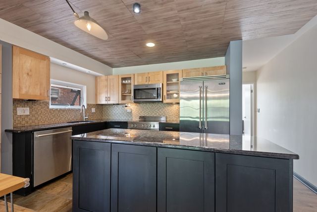 a kitchen with granite countertop cabinets stainless steel appliances a sink and a window
