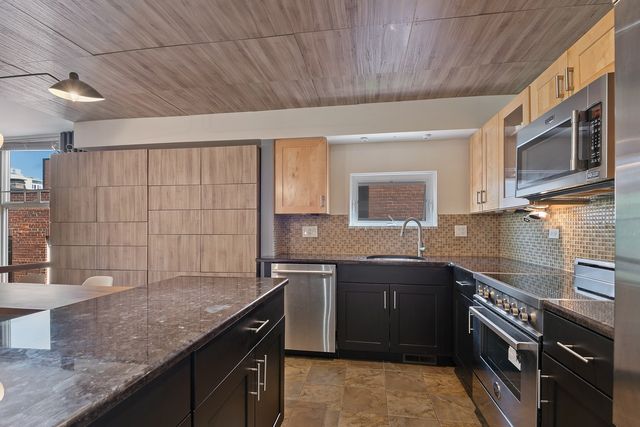 a kitchen with stainless steel appliances granite countertop a sink stove and cabinets