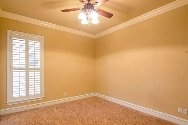 an empty room with a chandelier fan and windows