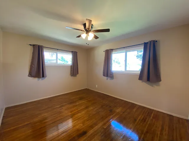 a view of an empty room with window and wooden floor