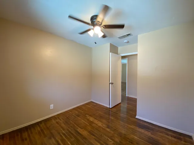 an empty room with wooden floor and a ceiling fan