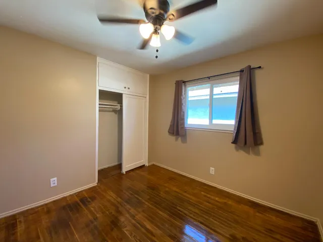 a view of an empty room with window and wooden floor