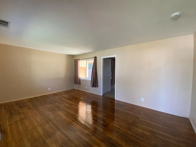 a view of an empty room with window and wooden floor