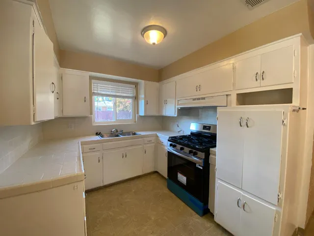 a kitchen with granite countertop appliances a sink cabinets and a window