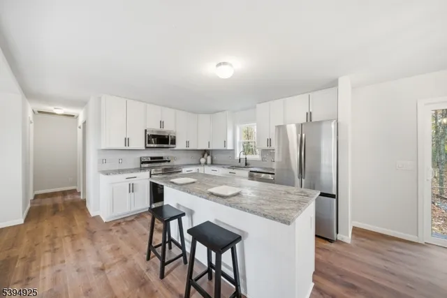 a kitchen with stainless steel appliances granite countertop a refrigerator stove microwave and white cabinets