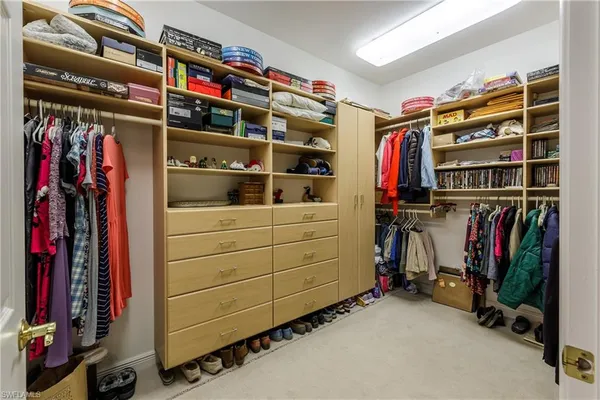 a view of walk in closet with clothes and shoes