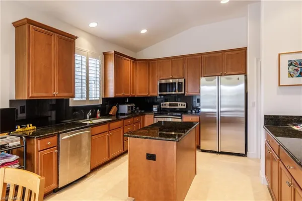 a kitchen with stainless steel appliances granite countertop a refrigerator a stove and a sink with wooden floor