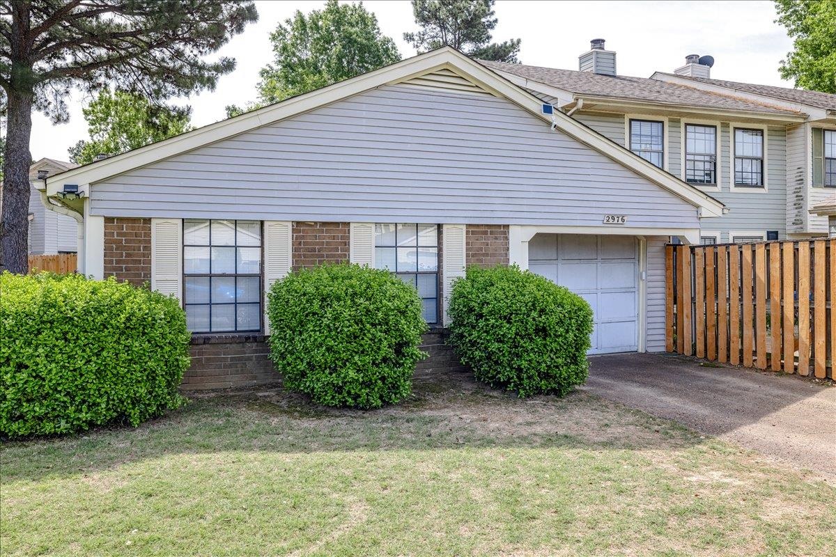2976 Kin Cove, Unit 2976 Memphis, TN 38119 - Photo 2 of 24 Front exterior featuring brick accents, horizontal siding, an attached garage, a driveway, and mature landscaping