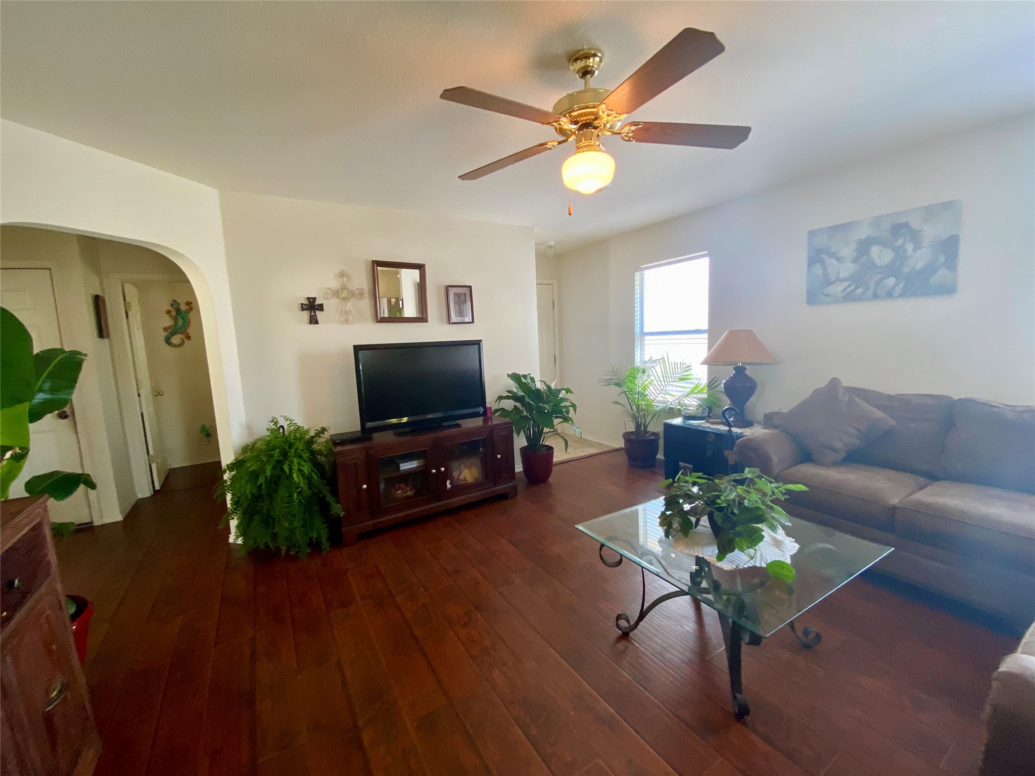 14420 Cummins Way Manor, TX 78653 - Photo 18 of 20 Spacious living area featuring wood-finish flooring, a ceiling fan with integrated lighting, and an arched doorway