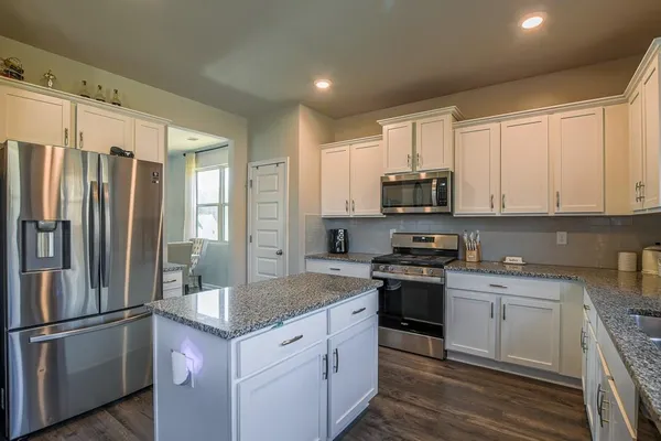 a kitchen with granite countertop a refrigerator stove and microwave