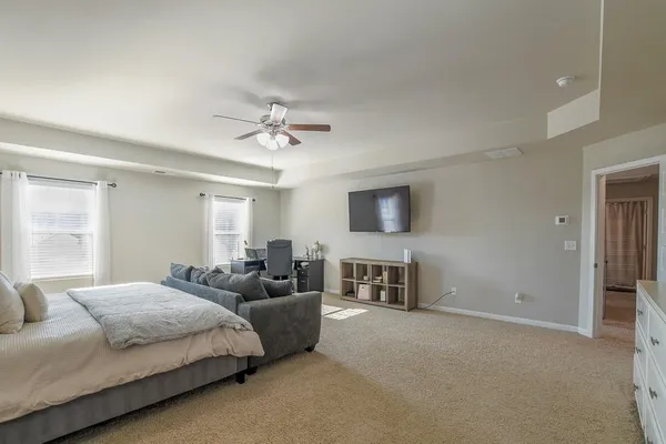 a spacious bedroom with a bed and a flat screen tv